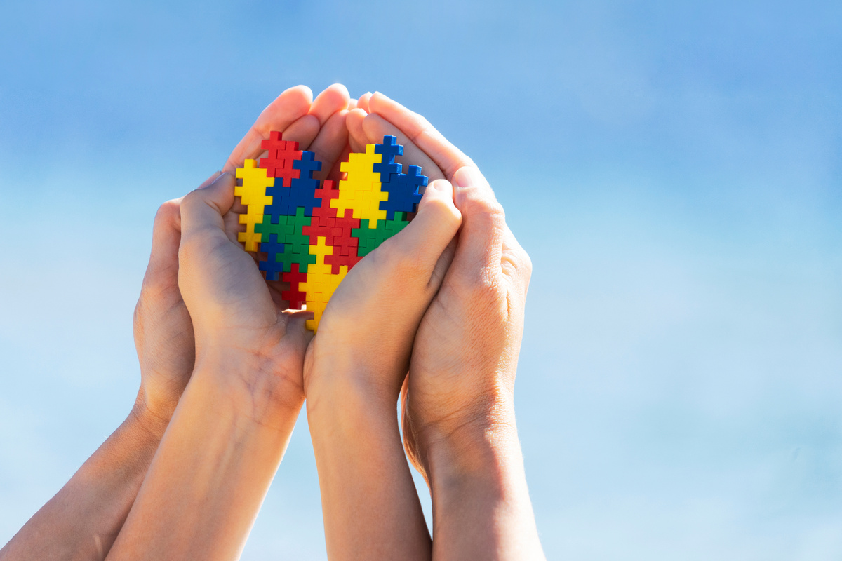 Child and Adult's Hands Holding a Multicolored Puzzle Heart